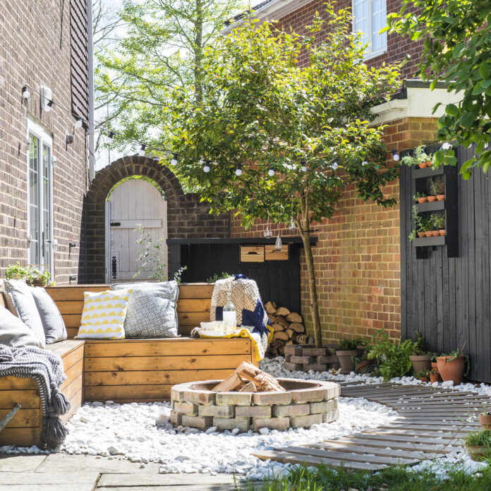 patio area with white stones, circular firepit and L-shaped built-in outdoor seating