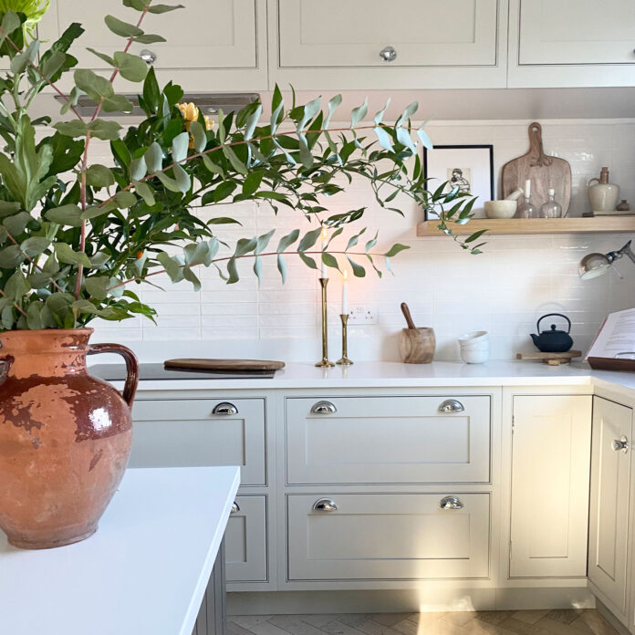 sage green kitchen with white tiles and worktops