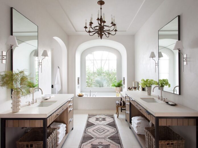 A primary bathroom with a traditional chandelier hanging over the tub.