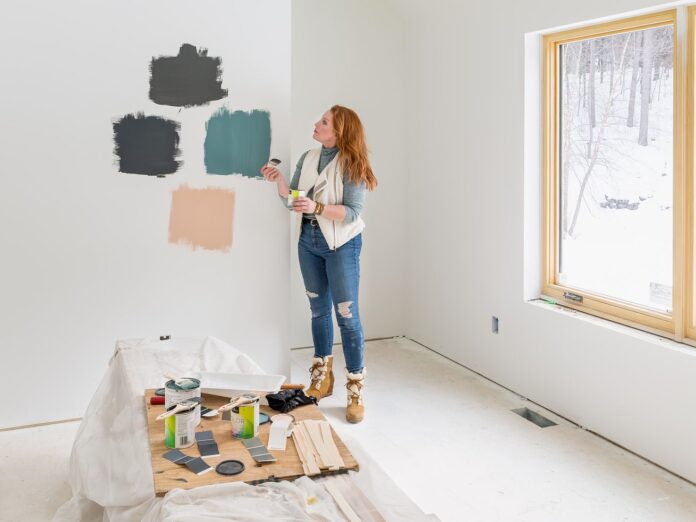 A woman putting up paint samples in a white room. 