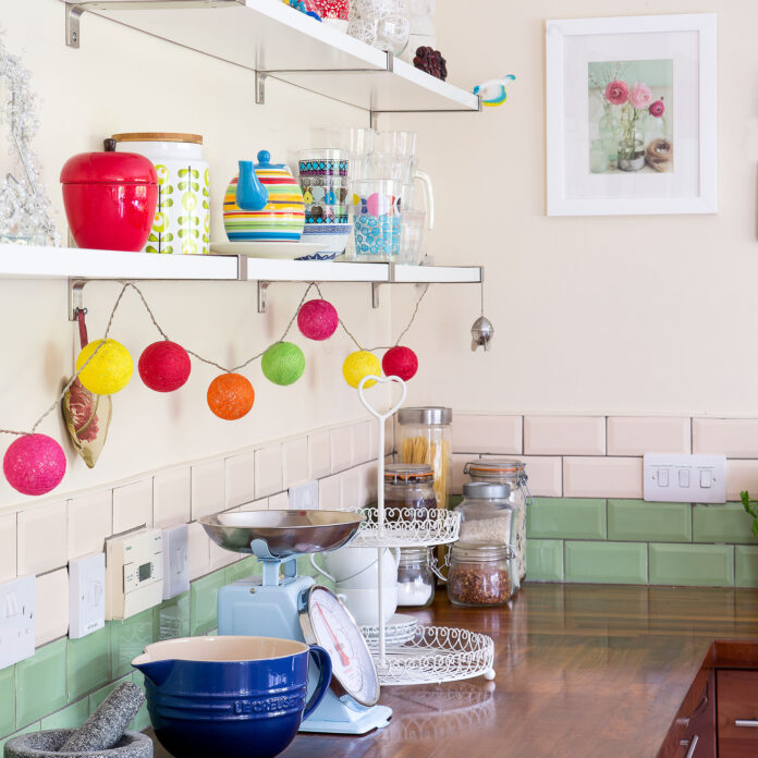 Cream kitchen with green and pink metro tile splashback and coloured string lights