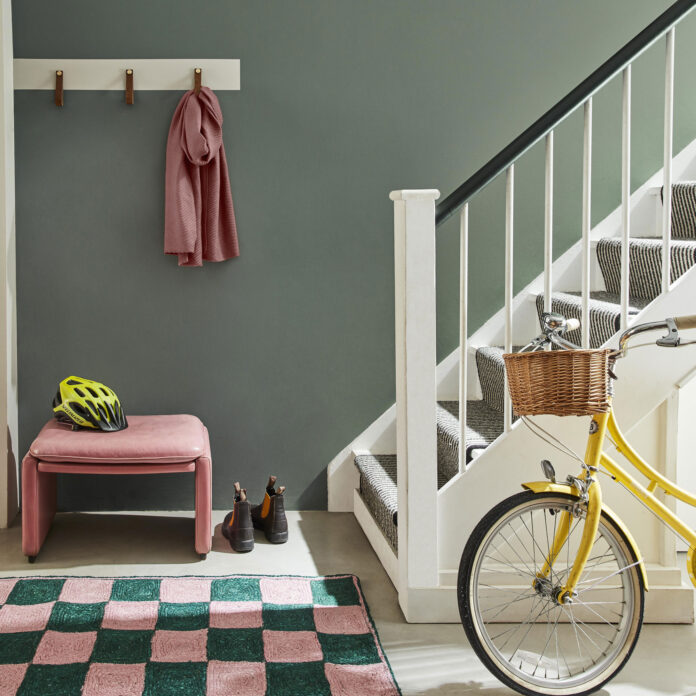 hallway with staircase and green wall and checkerboard rug in pink and green