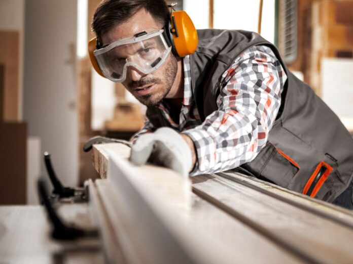 Man wearing safety gear to cut wood