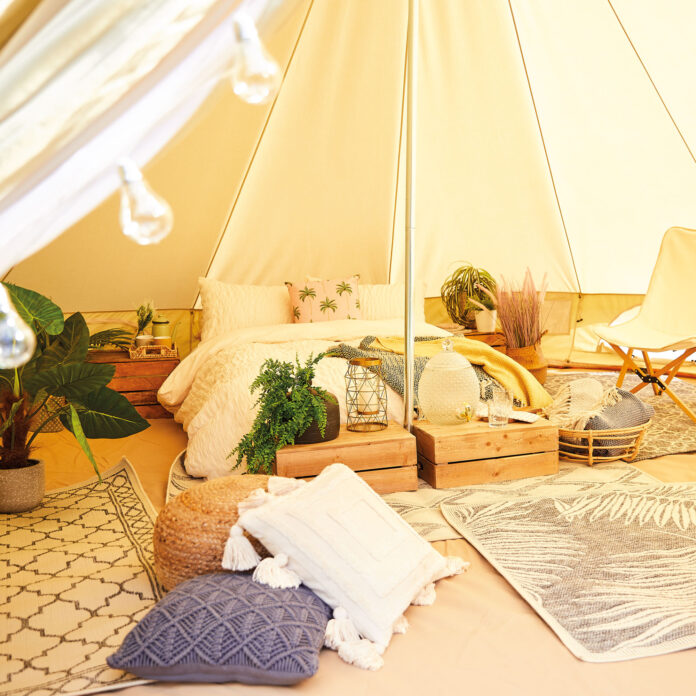 interior of aldi bell tent with bed, cushions and outdoor rugs