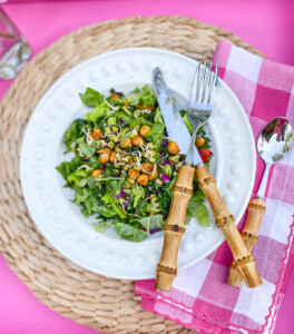 white dinner plate with salad on it. On a pink tray to dine alfresco.