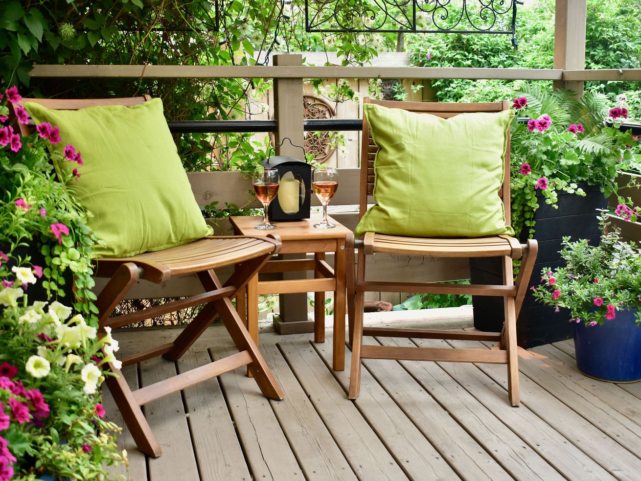 Deck with two chairs and green pillows.