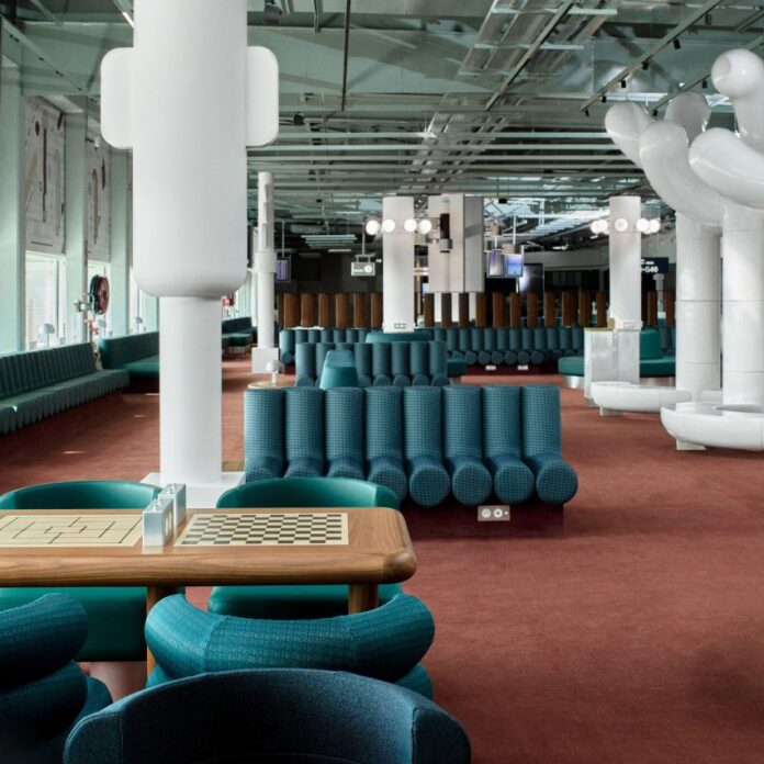 Photograph showing airport departure lounge with green bench seats and large tree-like rounded white sculptures