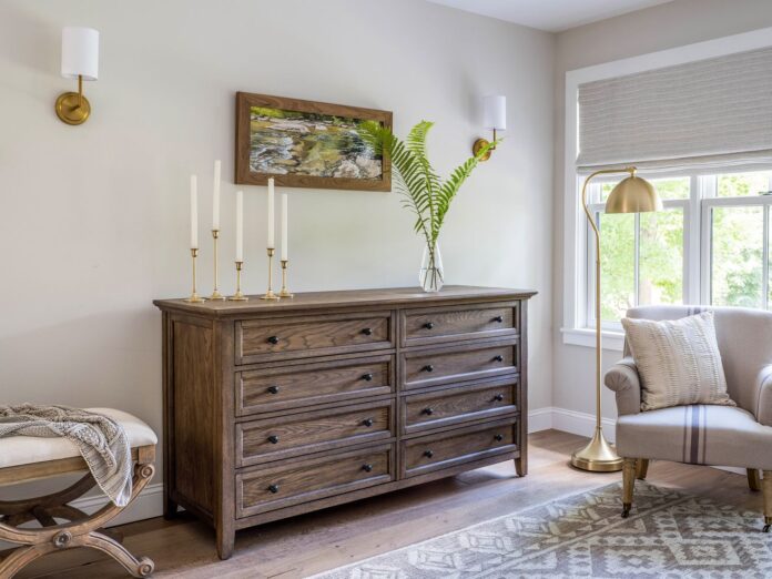 A bedroom with wall sconces mounted over a dresser 