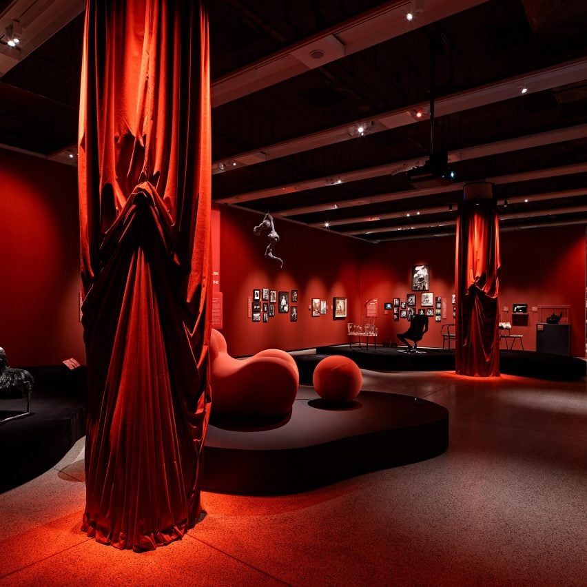 Chairs, sofas, red curtains and other objects displayed within the exhibition