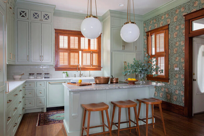 Kitchen renovation with mint green cabinets and an accent wall with floral wallpaper.