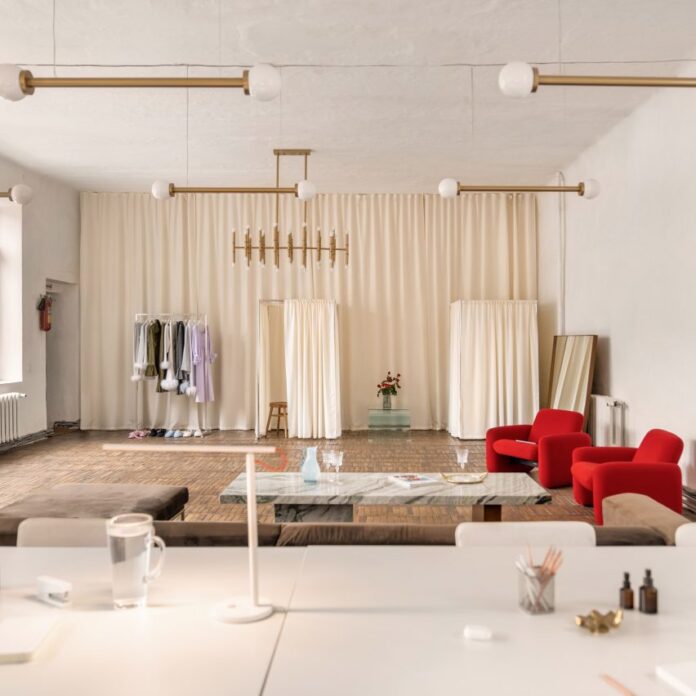 Photograph showing lounge area with brown-grey velvet sofa and red rounded armchairs