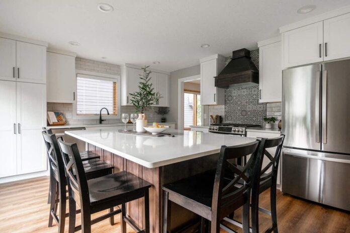 White shaker kitchen cabinetry with dark wood stained island and wood kitchen hood