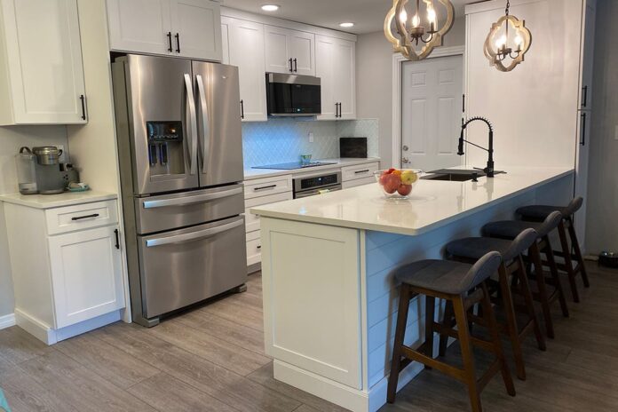 One-wall white shaker kitchen cabinets with shiplap island and rustic pendant lighting