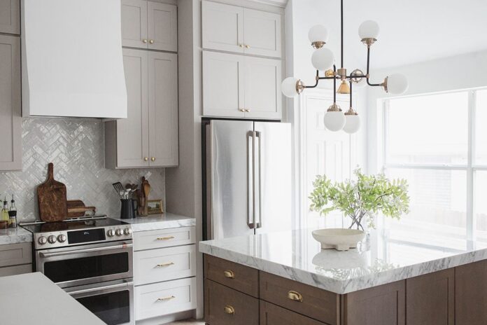 Light gray shaker kitchen cabinets and chestnut stained island with marble countertops and white, gold, and black accents