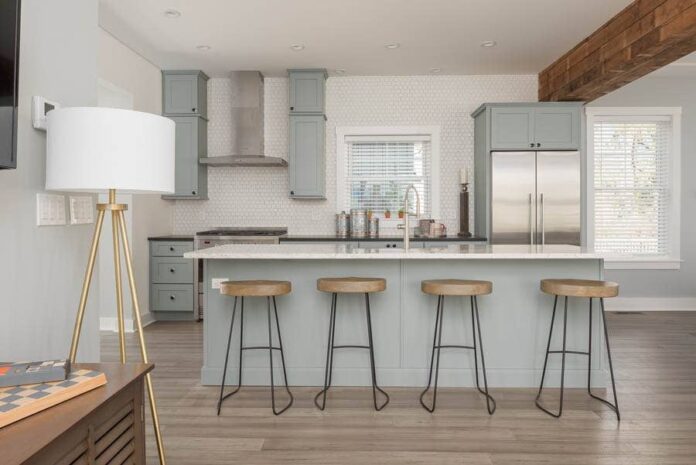 open kitchen with island seating for four with blue-gray cabinets and white backsplash up the wall