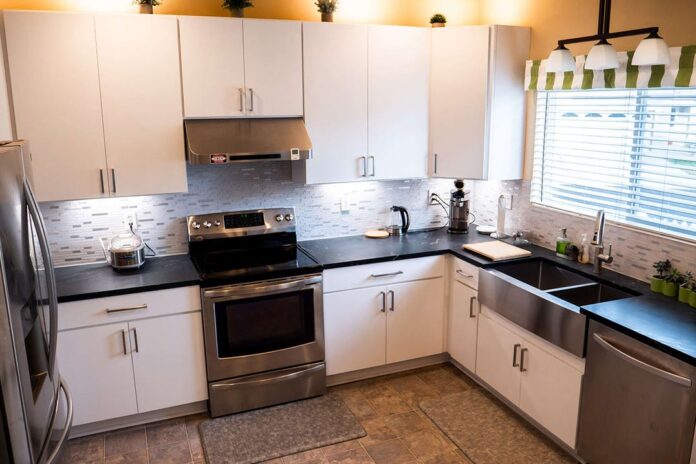 Slab white kitchen cabinets with stainless steel appliances and stainless steel apron sink