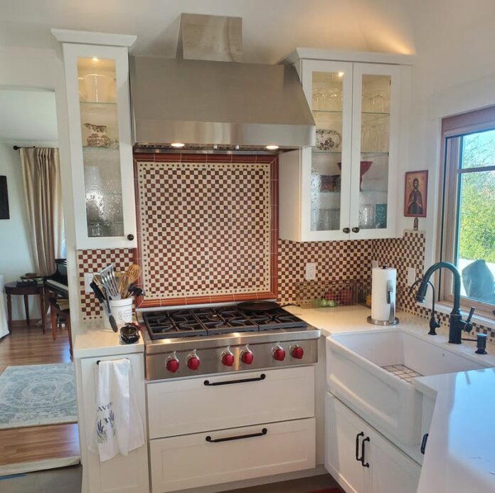 White shaker kitchen cabinets with a large white farm sink and Italian-style tile backsplash