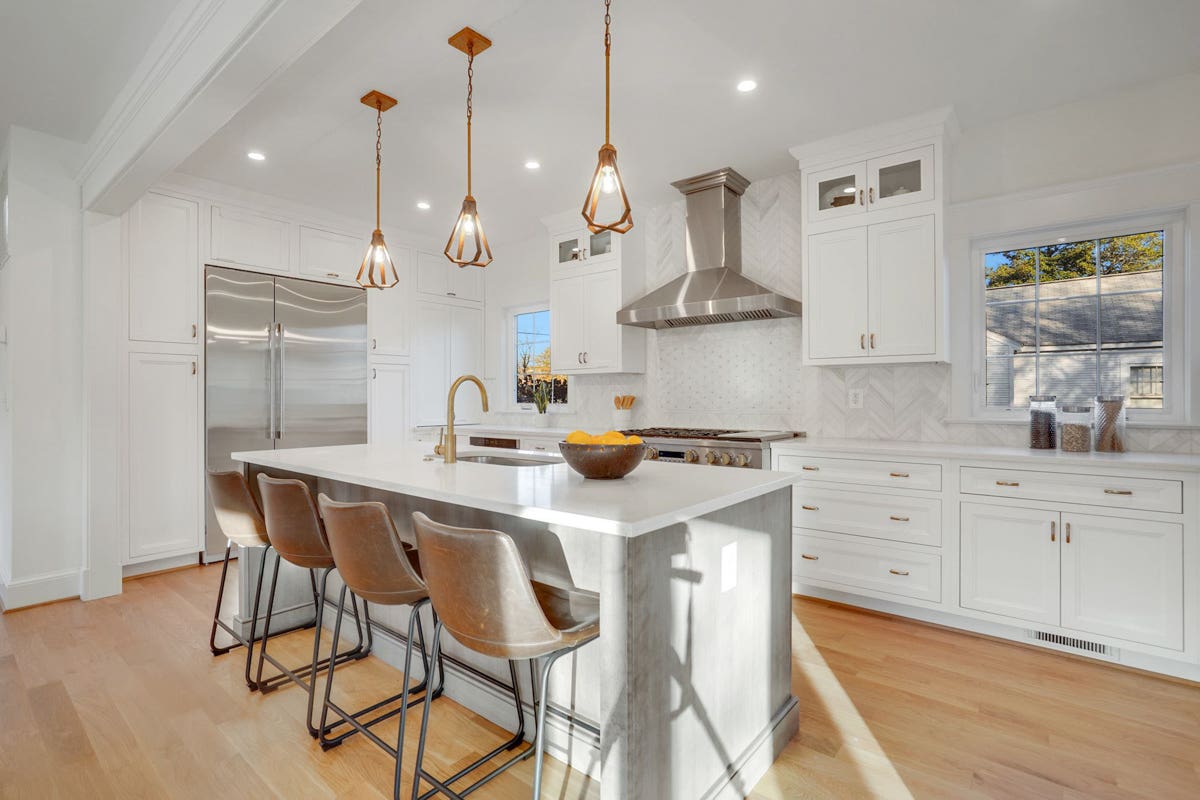 Stacked white shaker inset kitchen cabinets with a light gray stained island and white quartz countertops