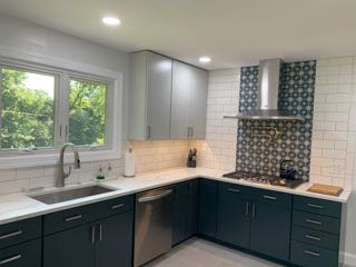 Light gray slab door wall cabinets and navy blue slab door base cabinets with white quartz countertops