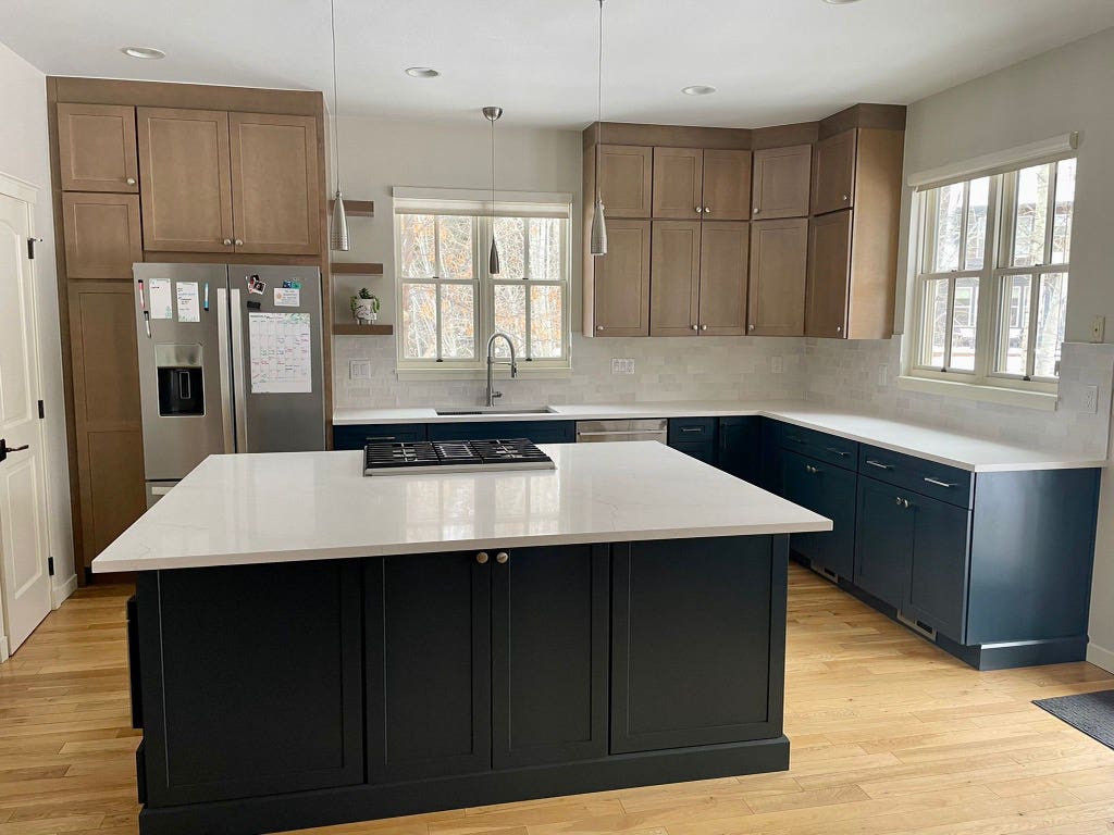 Light wood shaker kitchen wall cabinets with indigo shaker base and island cabinets with white quartz countertops