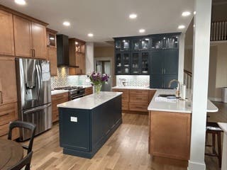 Light wood kitchen cabinets with indigo furniture-style accents and white quartz countertops