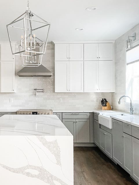 White and light gray shaker kitchen cabinets with white quartz waterfall countertops and polished chrome light fixtures