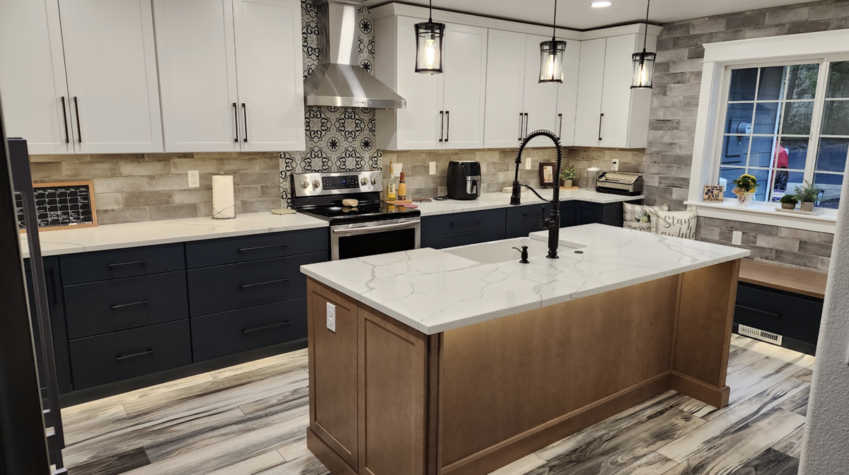 Farmhouse kitchen with white shaker wall cabinets, blue shaker base cabinets, and light wood furniture-style island