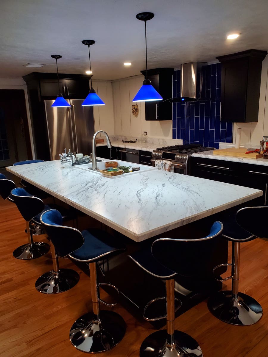 Black shaker kitchen cabinets with white countertops, blue lighting, and blue subway tile backsplash