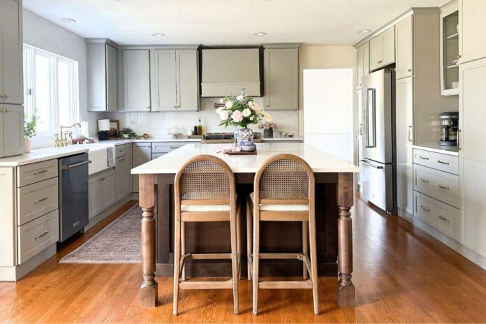 Light gray shaker kitchen with wood hood, white quartz countertops, and a large dark brown furniture-style island