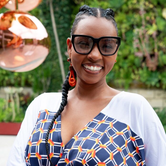 Woman in an outdoors setting wearing sunglasses and a blue and orange top 