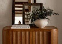 Antique mirrors sit on a vintage curved entry cabinet.