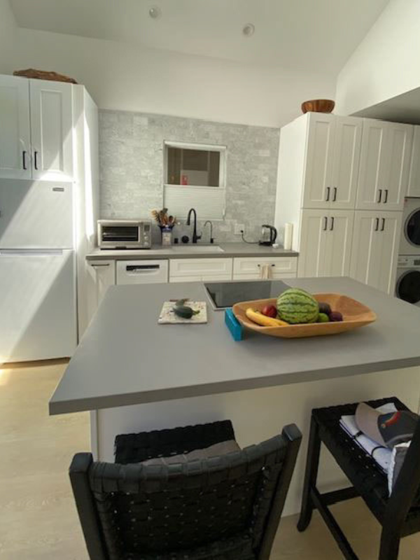 Contemporary white shaker kitchen and island with integrated stacked laundry and medium gray quartz countertops
