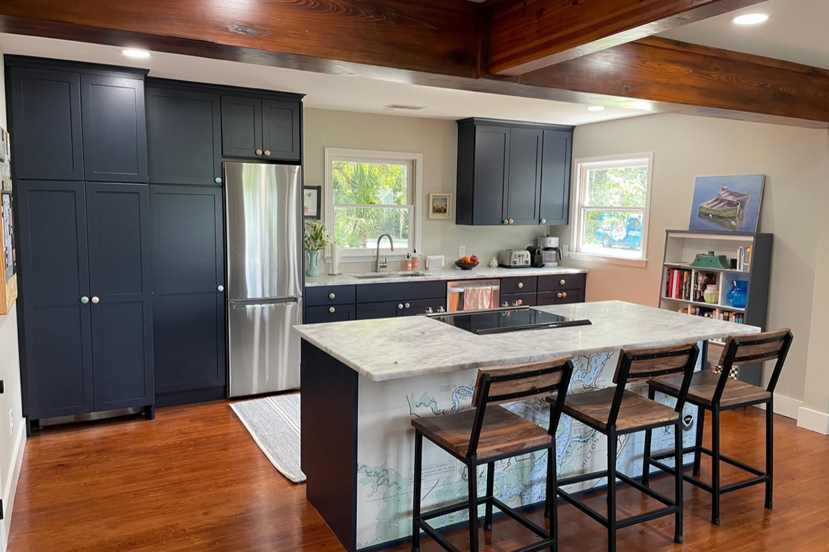 One-wall kitchen remodel with island in navy blue shaker kitchen cabinets with a white and gray quartz countertop and unique map of hilton head on the back of the island