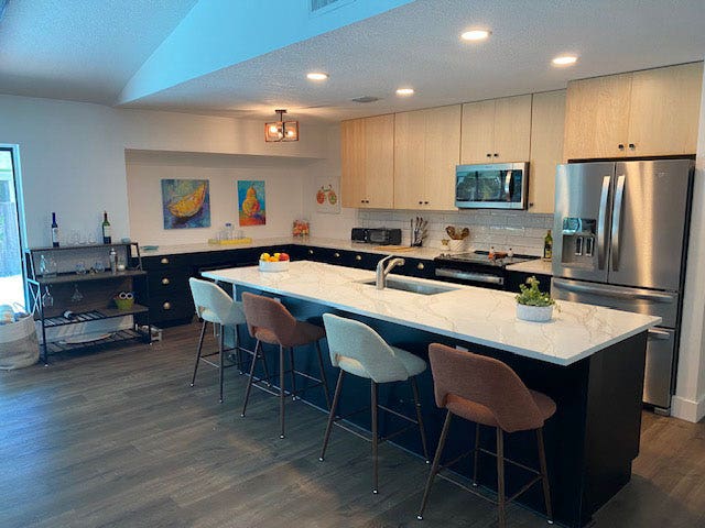 L-shaped kitchen design and island with black shaker base cabinets and natural maple wall cabinets.