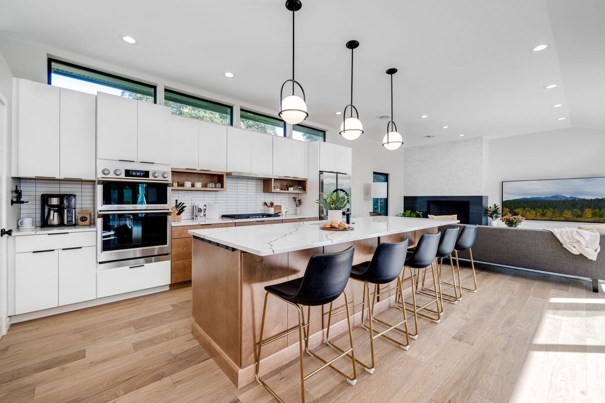 Mid-century modern kitchen design with white slab cabinets along one wall with warm wood base cabinets and accents plus a warm wood kitchen island and white quartz countertops