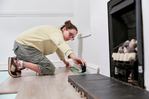 woman using measuring tape to measure space on floor