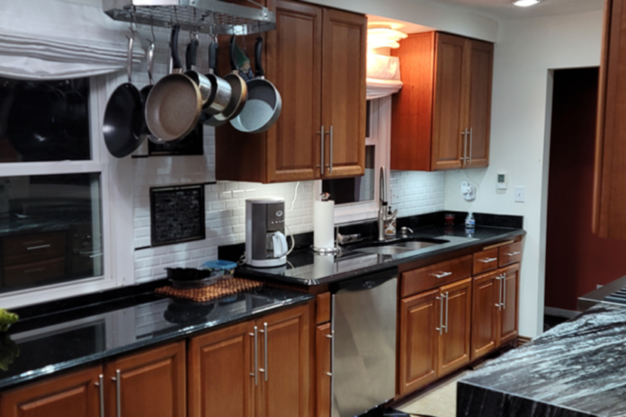 Raised panel cherry wood kitchen cabinets with black granite countertops and a waterfall edge