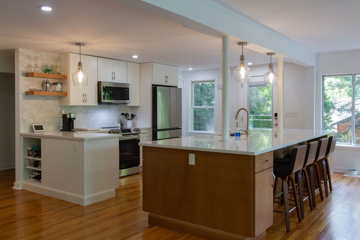 White slab door kitchen design with a warm wood island and glass pendant lights