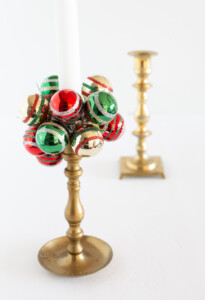 Brass candle holder with green red and gold mini Shiny Brite ball ornaments made into a taper candle collar.