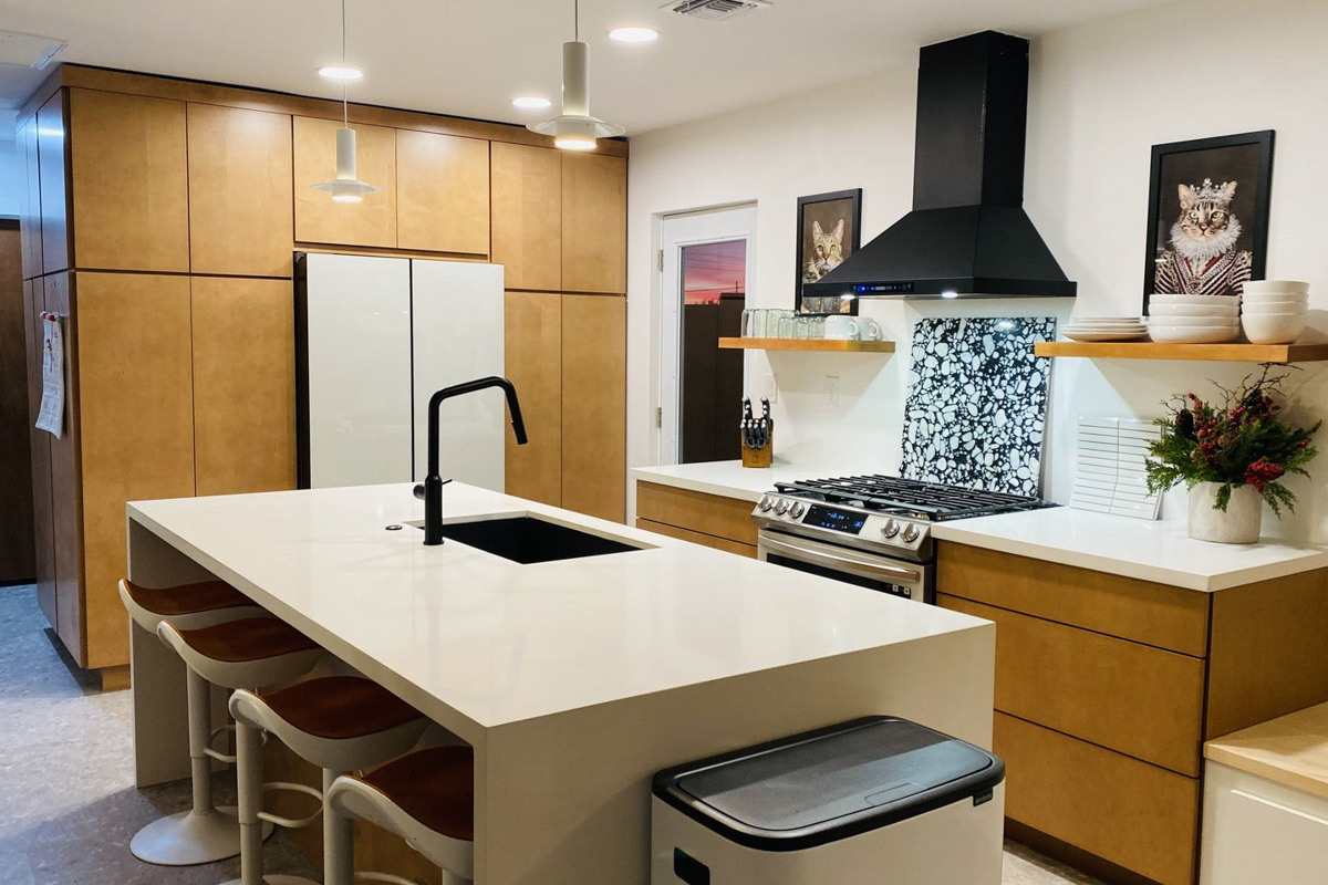 Mid-century modern kitchen design with light brown slab kitchen cabinets and a cream-colored waterfall quartz countertop