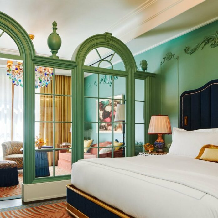 Hotel room with classical green wooden framing separating the lounge area from the bed