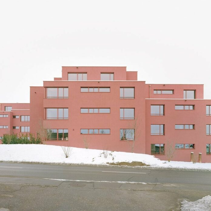 Ductus coats blocky apartment complex with red plaster in Switzerland