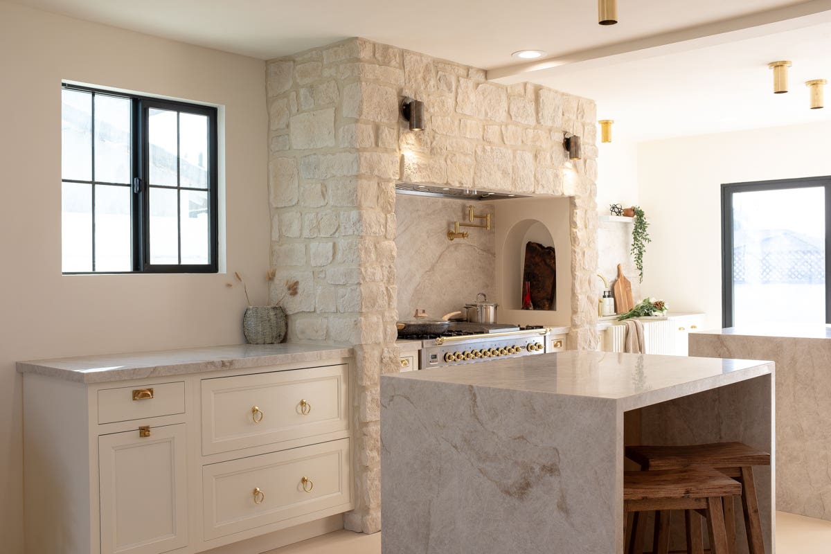 White inset shaker kitchen cabinets on a range wall with built-in Mediterranean stone alcove for the range