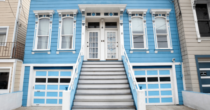 Exterior of a blue duplex with white doors.