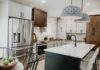 Tri-tone kitchen design with skinny shaker cabinets in light gray and medium brown with a black island and white stone countertops