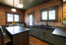 U-shaped large green kitchen with inset cabinets, vintage elements and dark brown island with black granite countertops and hardware