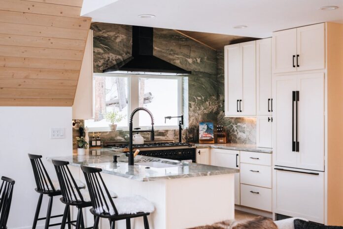 U-shaped white shaker kitchen design with modern black handles and green natural stone countertops and slab backsplash
