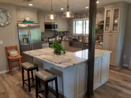 L-shaped kitchen design with L-shaped island in cream colored raised panel kitchen cabinets
